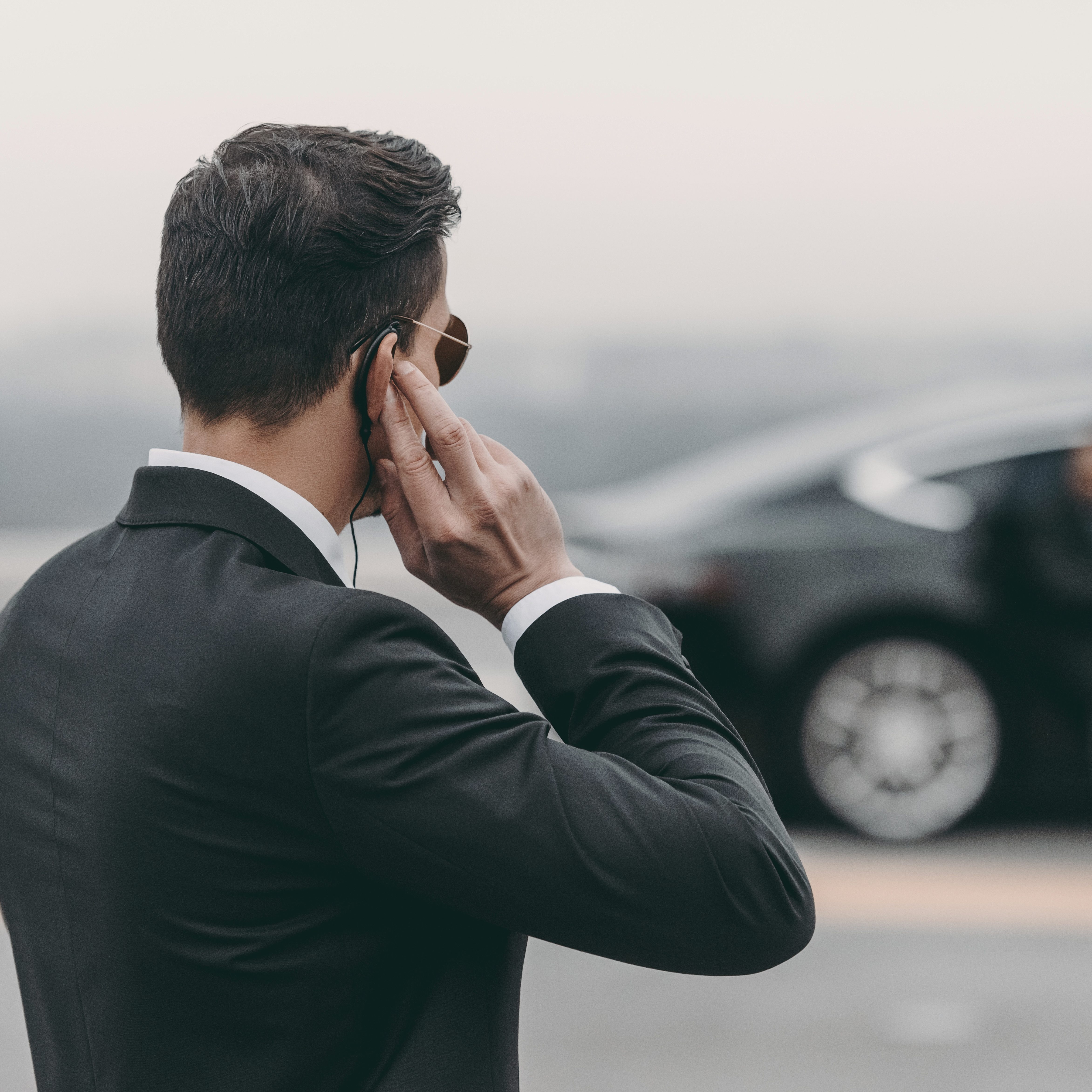 handsome bodyguard standing and listening message with security earpiece on helipad