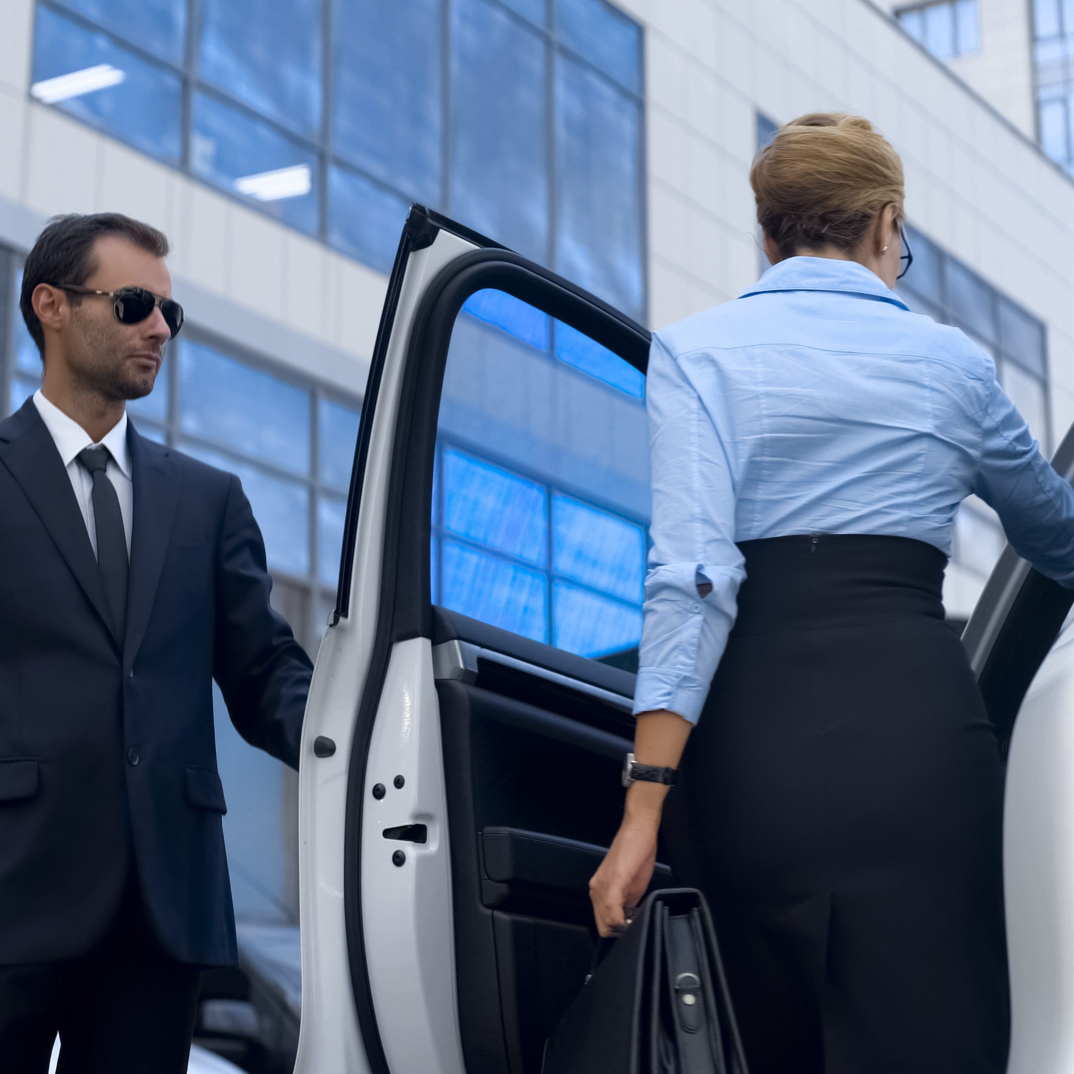 Personal assistant of female politician opening car door to his boss, service